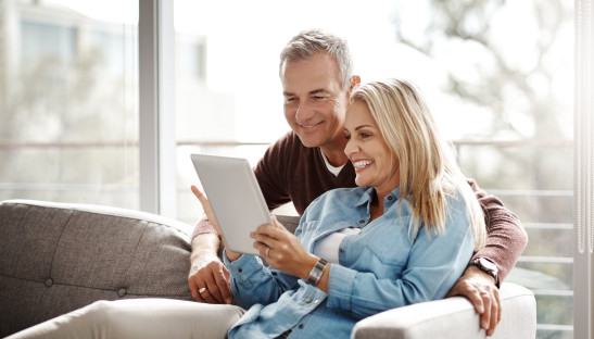 Paar sitzt mit Tablet auf einem Sofa