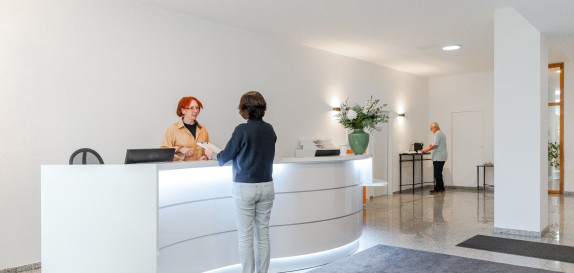 Patientin bespricht etwas mit MFA an der Anmeldung