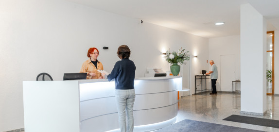 Patientin bespricht etwas mit MFA an der Anmeldung