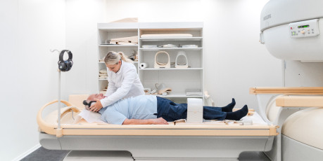 MFA kümmert sich um ältereren Patient mit Kopfhörern auf Liege